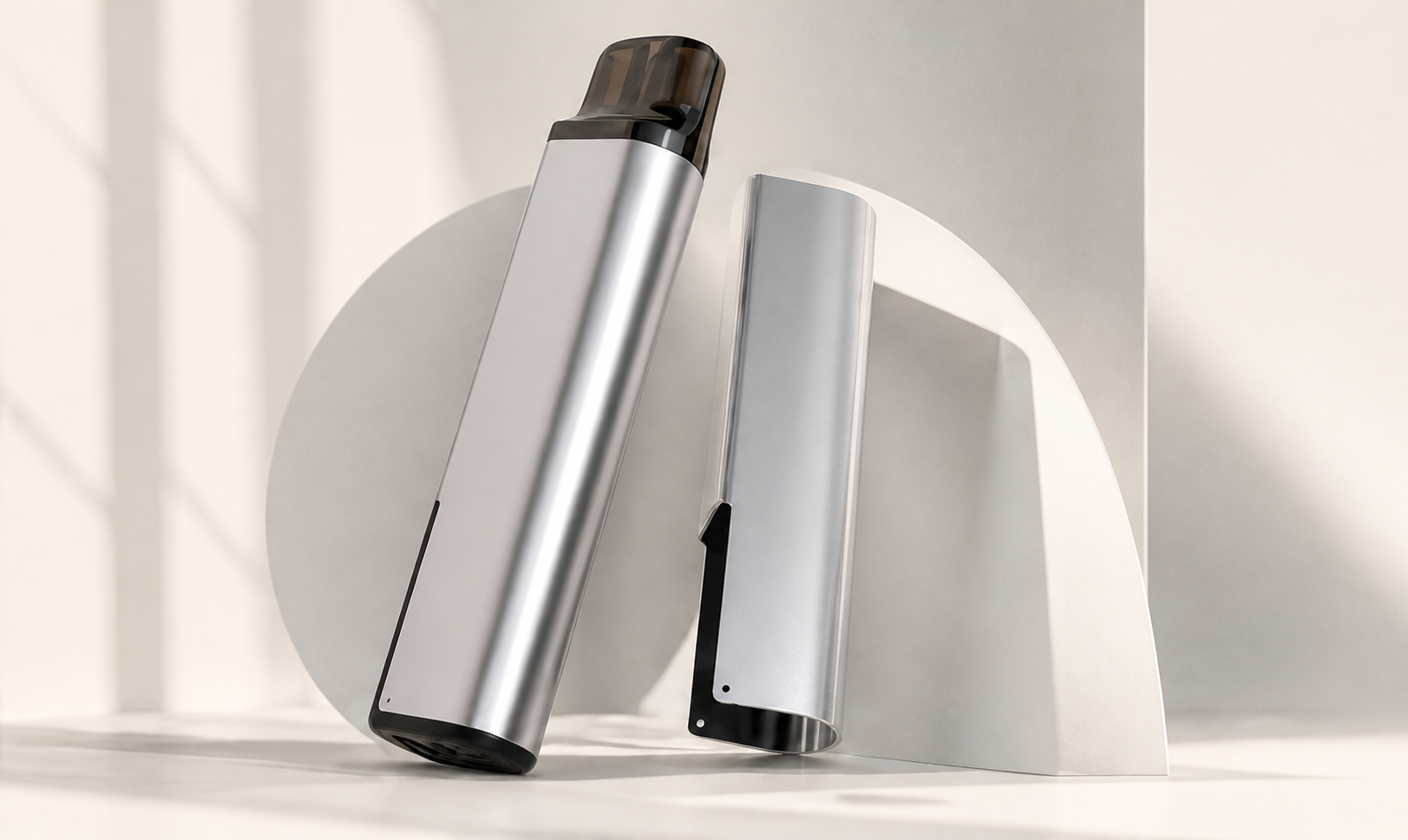 Two silver refillable vape devices against warm ivory architectural arches